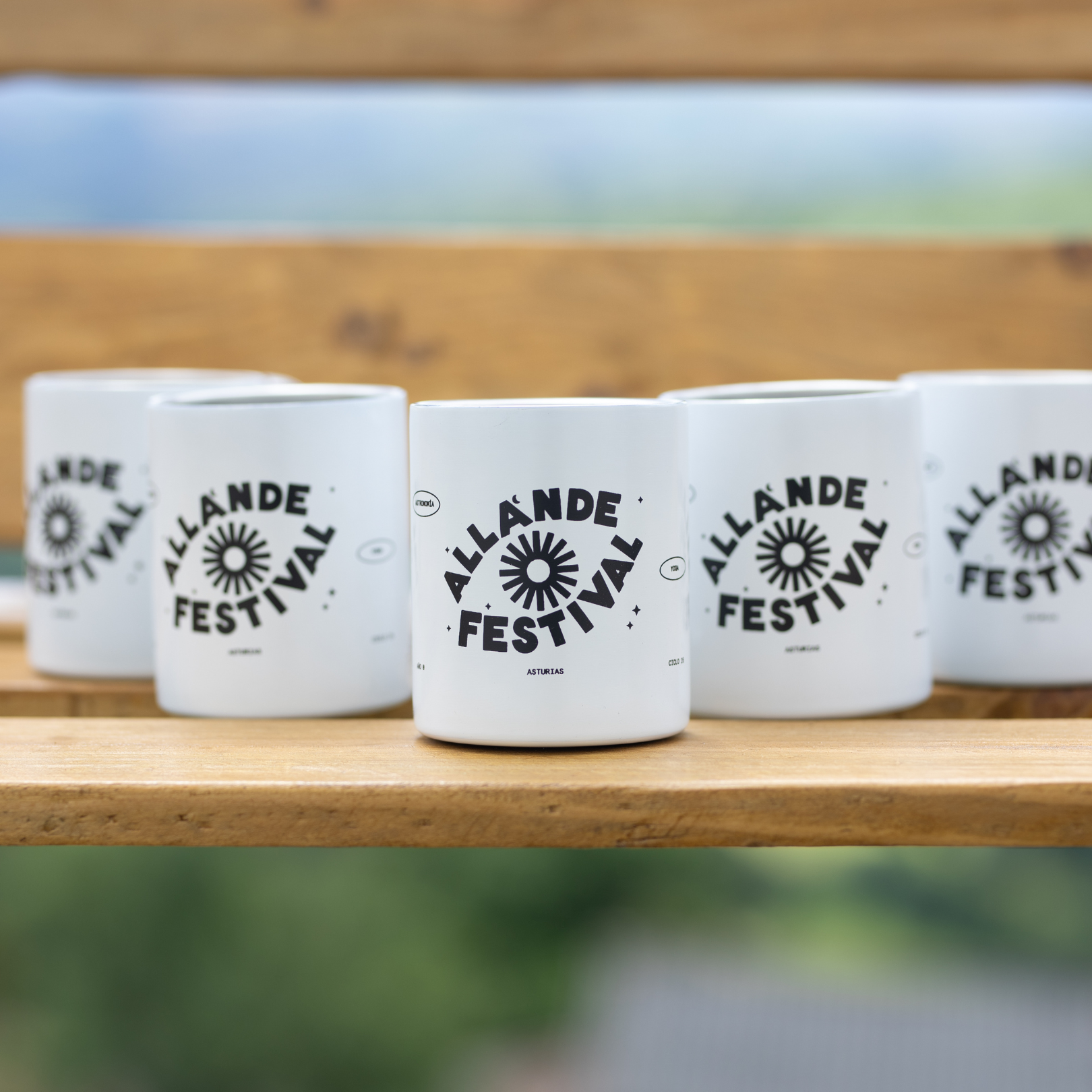 Cinco tazas del Allande Festival sobre un banco